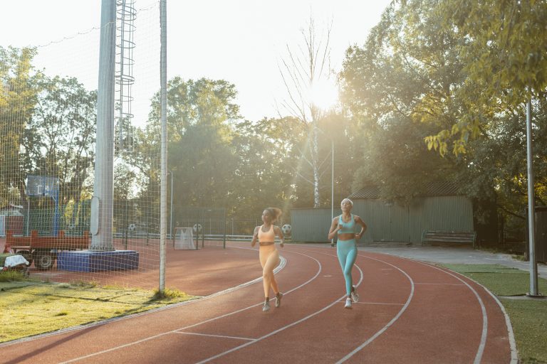 İstanbul'da koşu grupları ile birlikte atletizm pistinde koşan iki kişi
