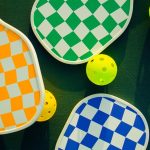 Yan yana dizilmiş çeşitli pickleball raketleri ve toplar