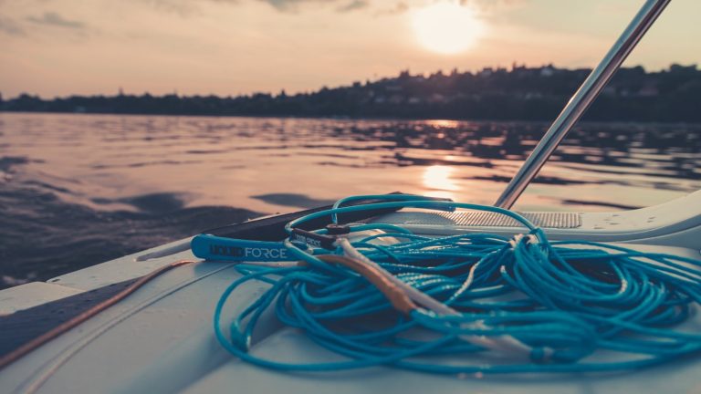 İlk Su Sporları Ekipman Seti Nasıl Oluşturulur? Başlangıç İçin Satın Alma Rehberi Kıyıda dizili su sporları ekipmanları — wetsuit, SUP ve palet