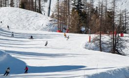 Karlı dağ pistinde aşağı inen kayakçılar ve snowboardcular