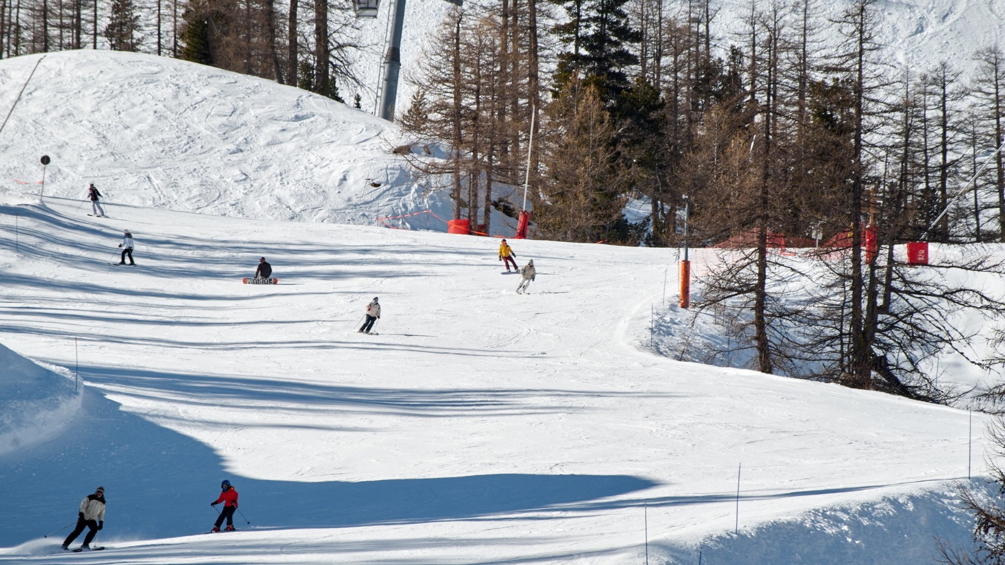 Skifahrer und Snowboarder bei der Abfahrt auf einer verschneiten Bergpiste