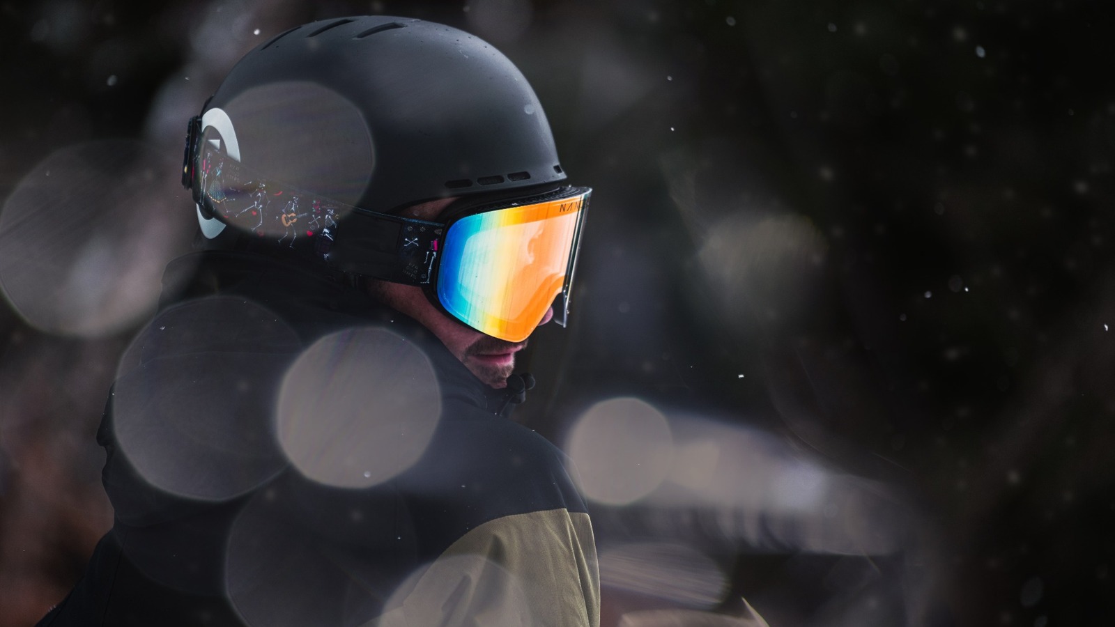 Ein oft übersehener Teil der Skibekleidung: Skifahrer mit schwarzem Helm und orange verspiegelter Skibrille bei Schneefall