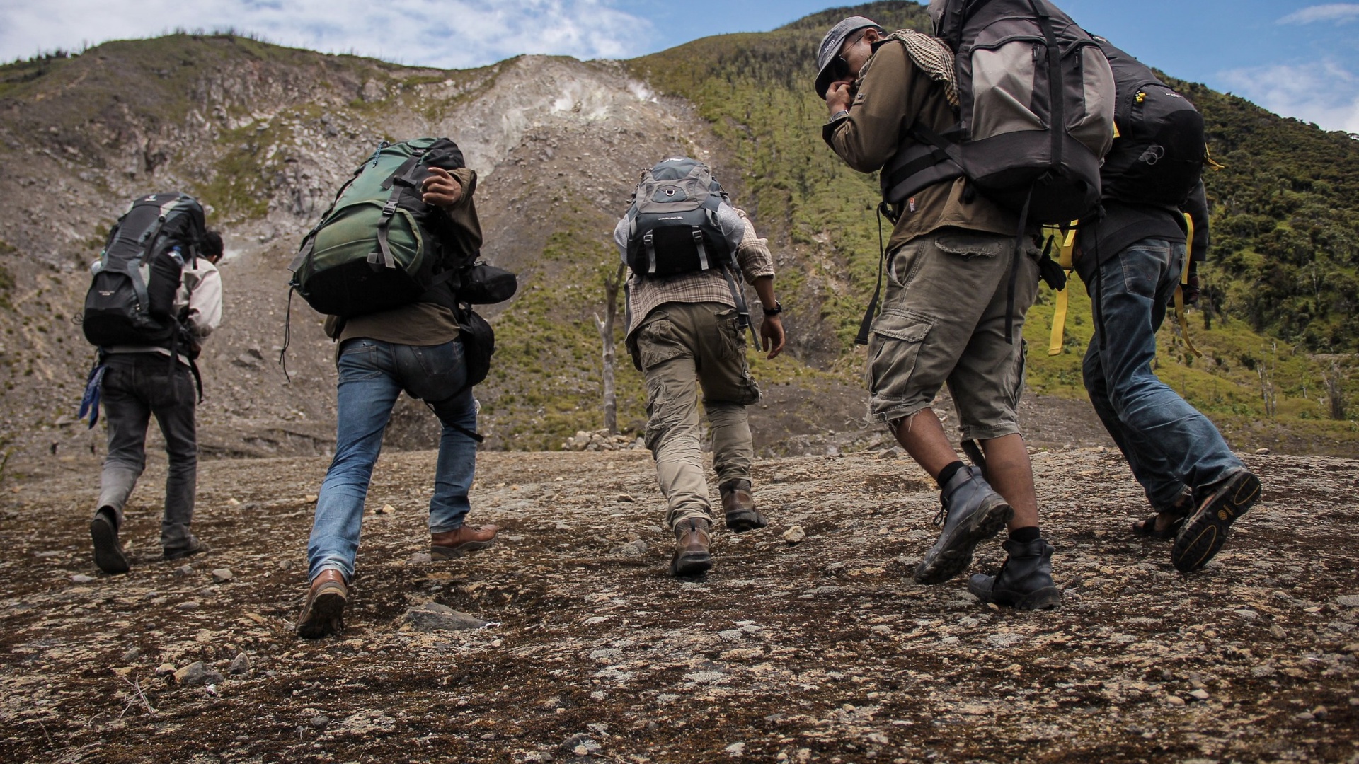 Trekking pantolonu ve outdoor kıyafetleriyle patikada yürüyen bir grup yürüyüşçü