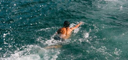 Açık su yüzmesinde dalgalı denizde serbest stil yüzen yüzücü
