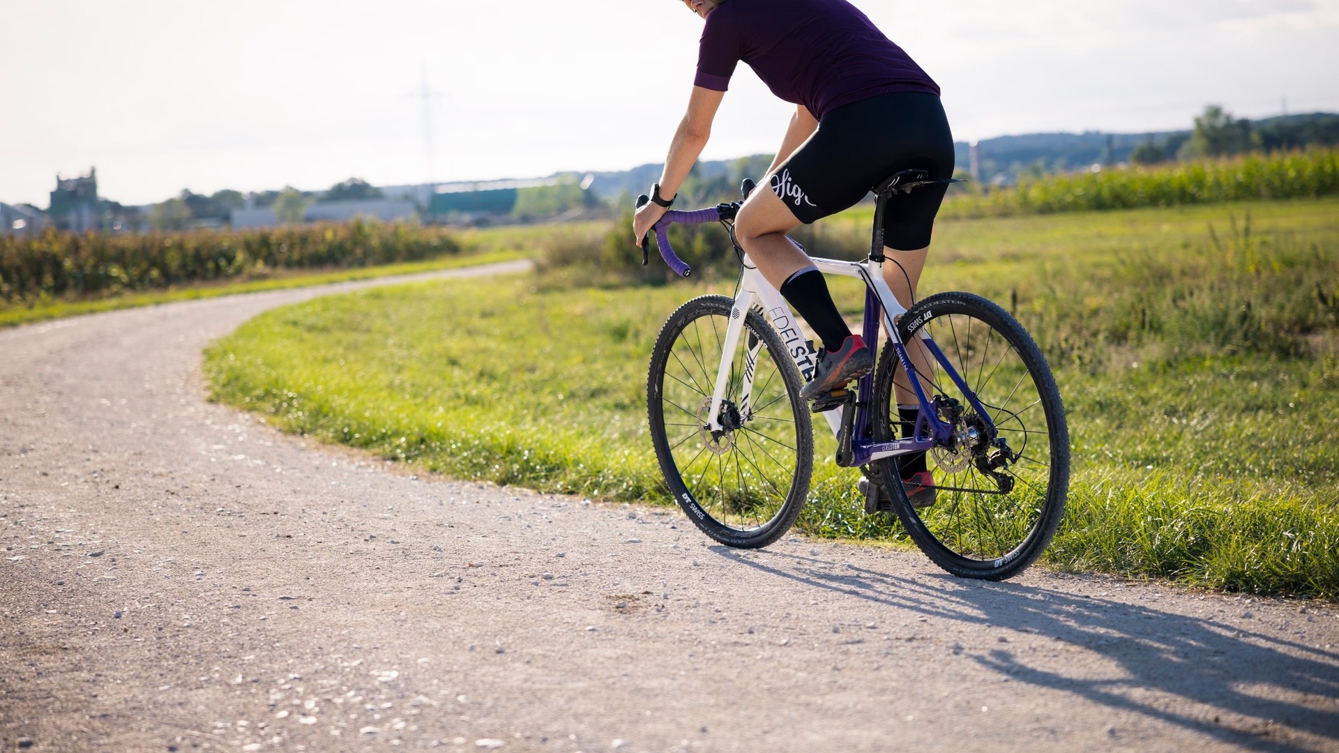 A gravel cyclist riding alone on a winding gravel road; most of a gravel race course is made up of off-tarmac surfaces like this