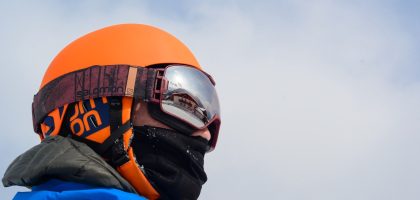 Turuncu kayak kaskının üzerinde aynalı lensli kayak gözlüğü takmış kayakçı