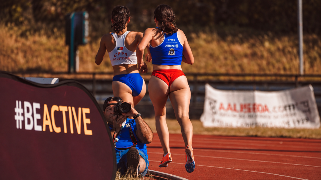 Atletizm pistinde önündeki sporcuyu takip ederek koşan kadın atlet