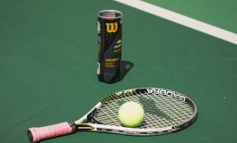 Tennisschläger mit Overgrip, Tennisbälle und Balldose auf dem Platz