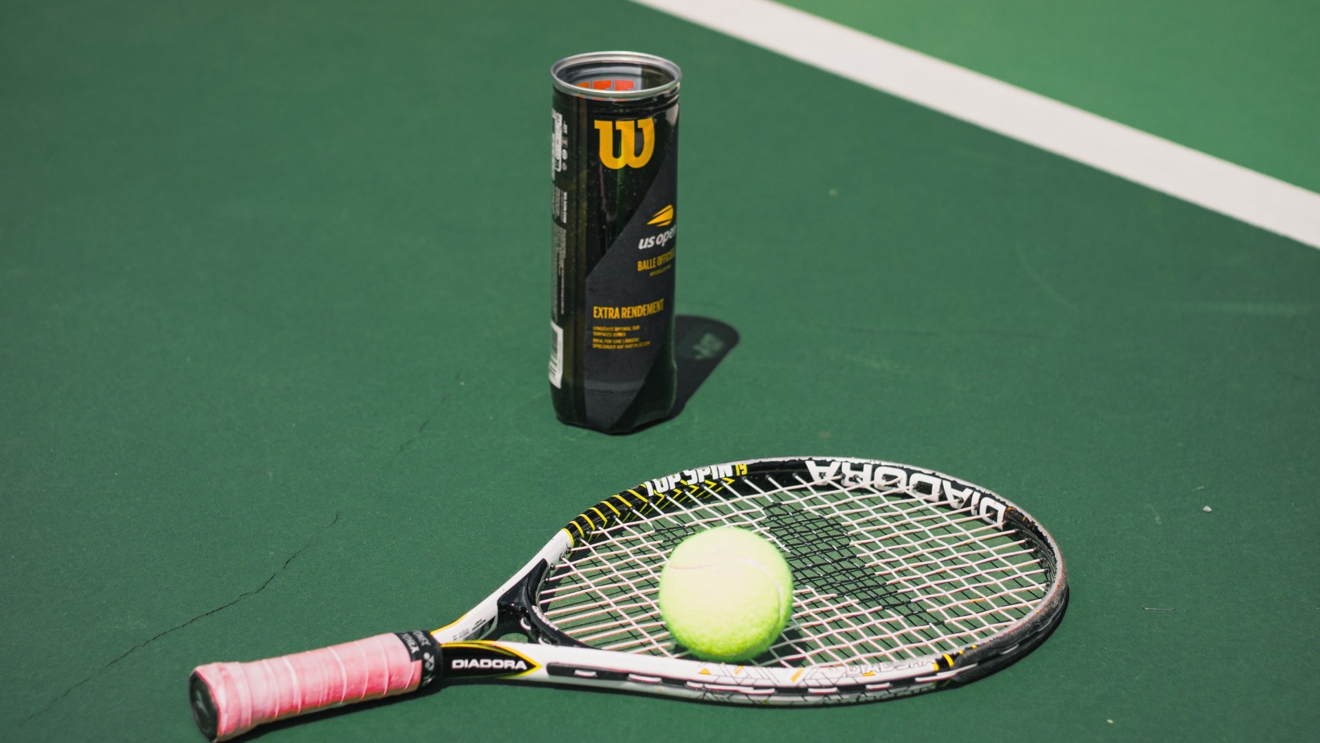 Kortta overgrip sarılı tenis raketi, tenis topu ve top kutusu