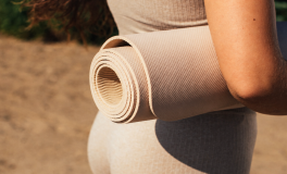 Açık havada rulo hâlinde taşınan bej renkli yoga matı