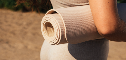 Açık havada rulo hâlinde taşınan bej renkli yoga matı