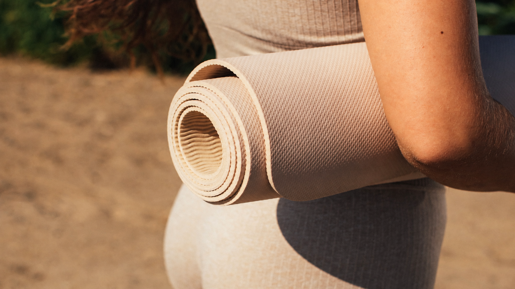 Açık havada rulo hâlinde taşınan bej renkli yoga matı