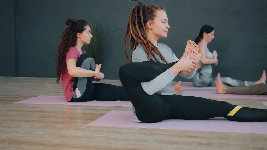 Stüdyoda matlar üzerinde oturarak yoga yapan üç kadın