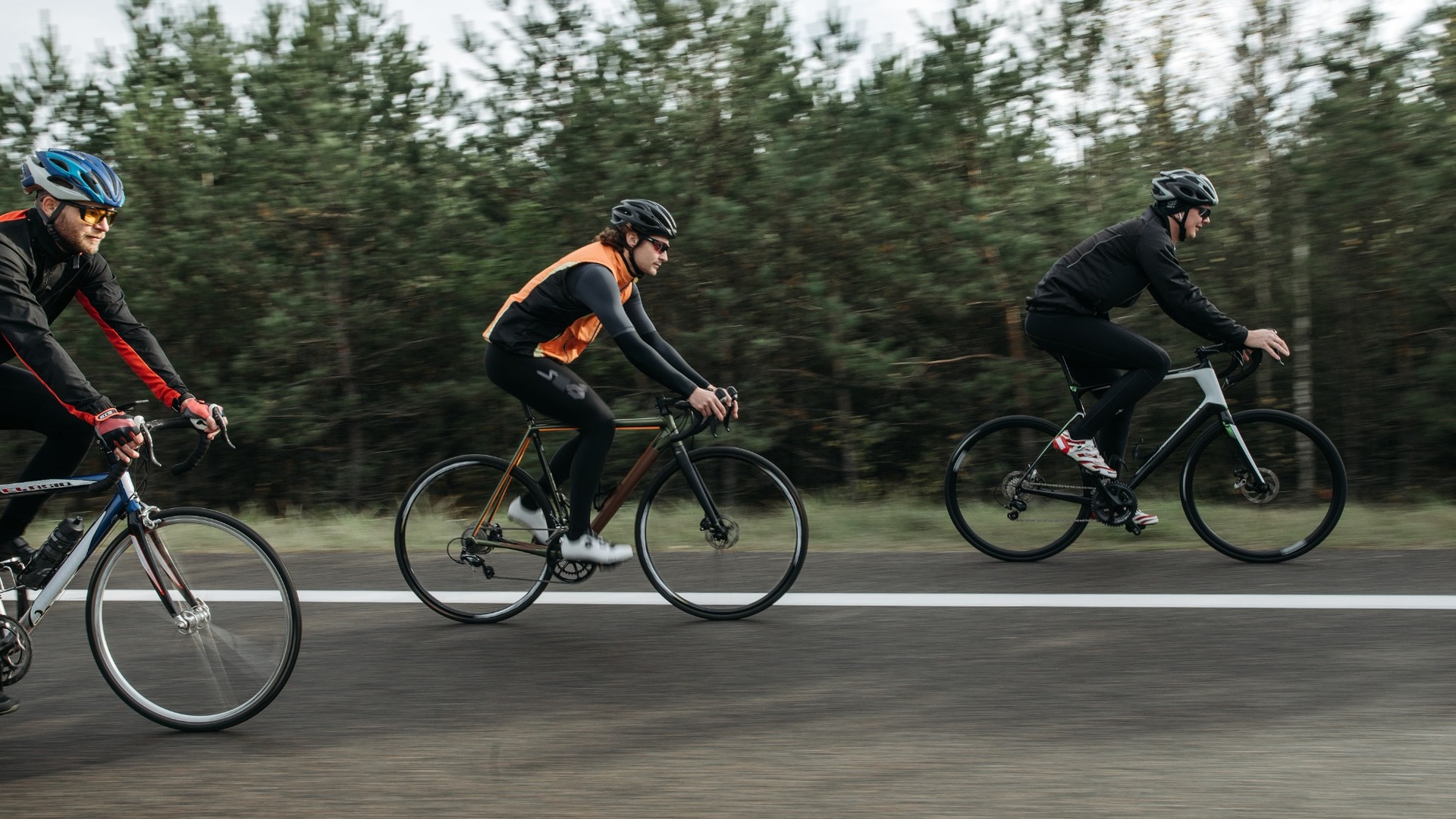 Three cyclists riding road bikes in long-sleeved layered clothing in winter