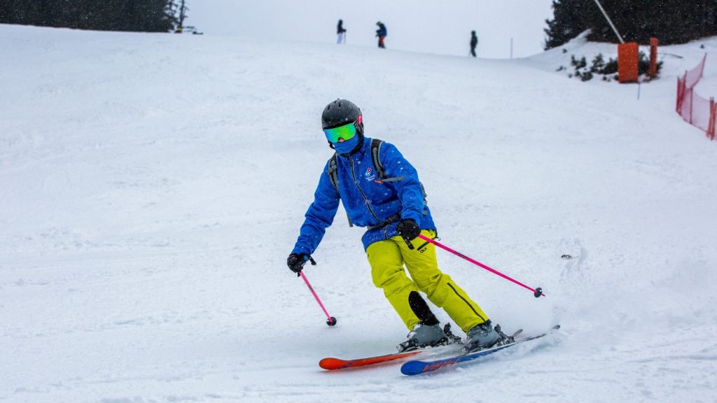 Skier in a helmet and goggles making a controlled turn on an easy blue run