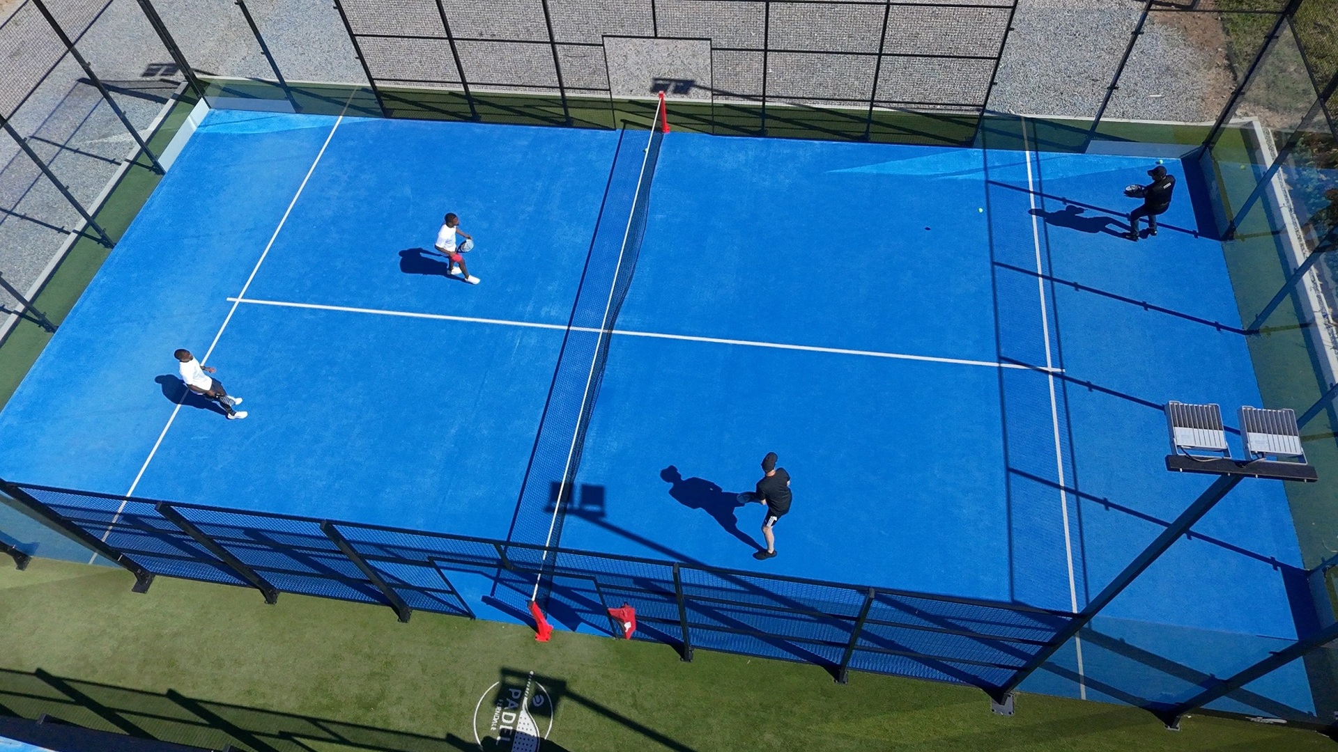 Padelde partnerinizle kortu paylaşmak: mavi zeminli açık padel kortunda çiftler maçı oynayan dört oyuncunun kuşbakışı görünümü
