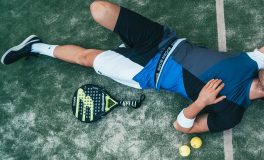 Padel kortunda yere uzanmış oyuncu, yanında padel raketi ve iki top; padel Americano turları arasında kısa bir mola