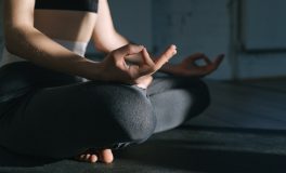 Woman sitting cross-legged on a mat with her hands resting calmly on her knees